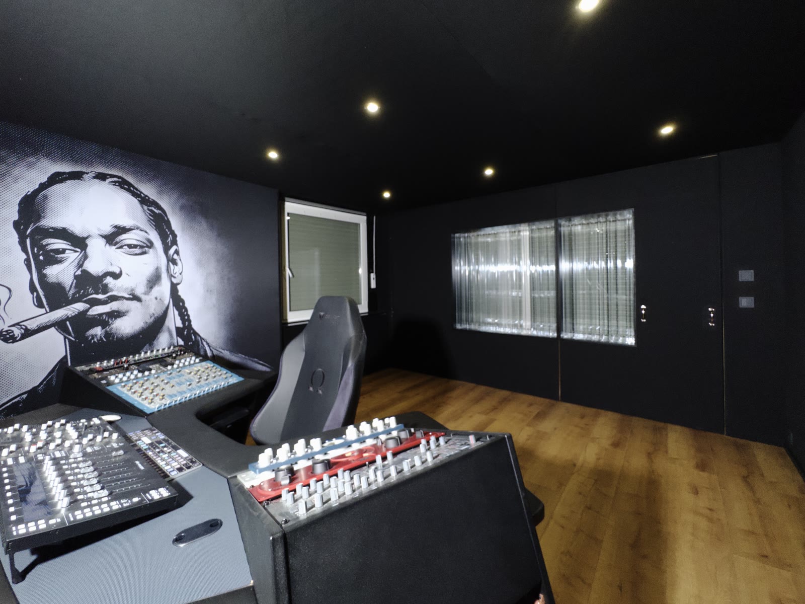 The command position at MMA Studios: analog processors from elysia and SPL within reach on the Argosy workstation wings, a large-format portrait mural on acoustically transparent fabric behind, daylight from the Lightffusor rear wall.